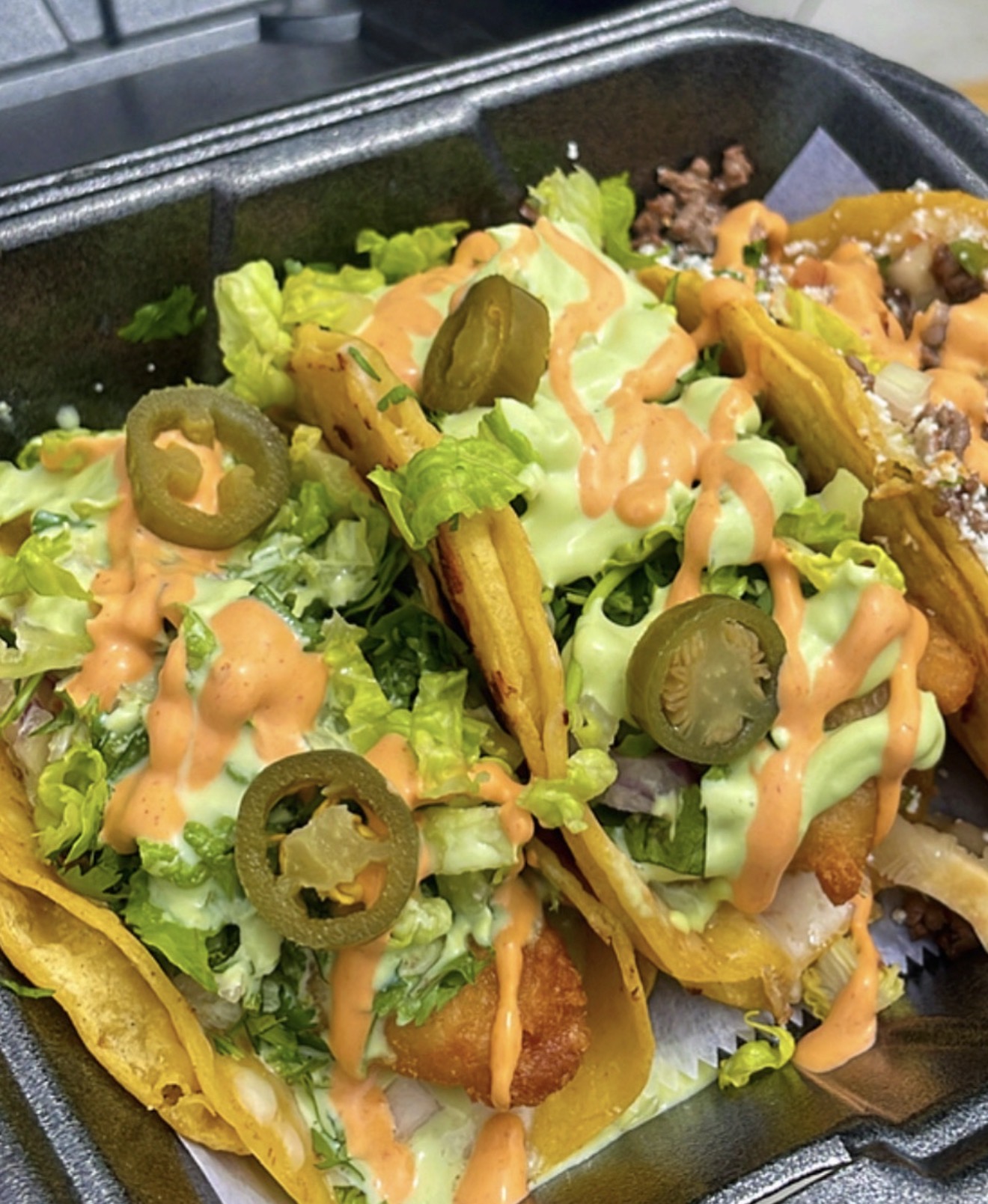 Loaded tacos with lettuce, jalapeños and colorful sauces
