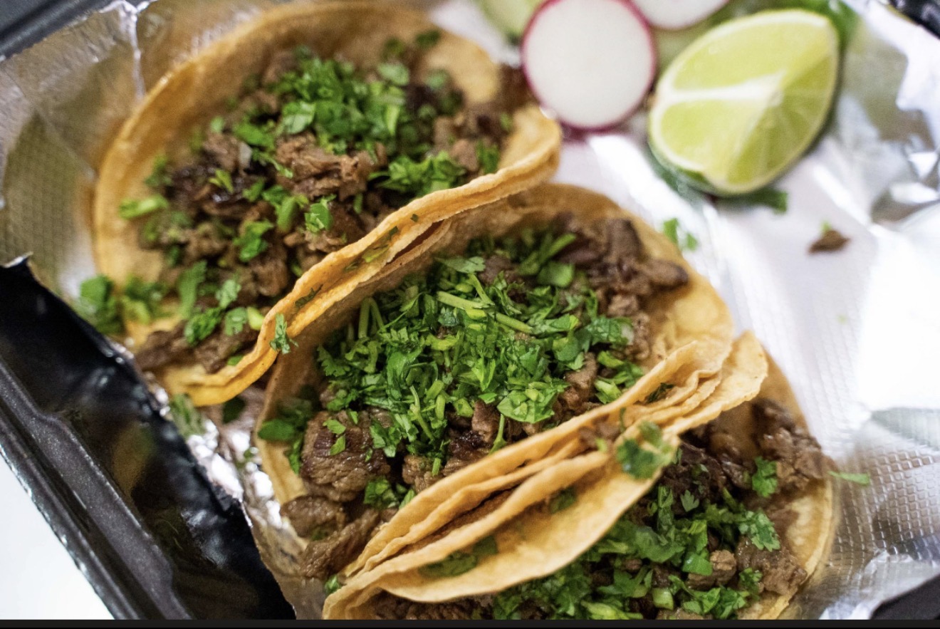 Three tacos topped with fresh cilantro alongside lime and radish